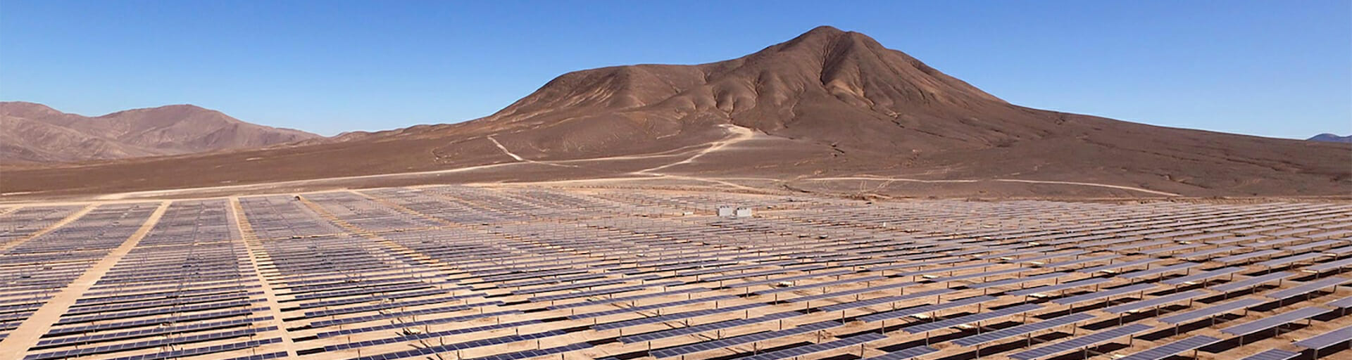 
		Field of solar panels with moutain in background		